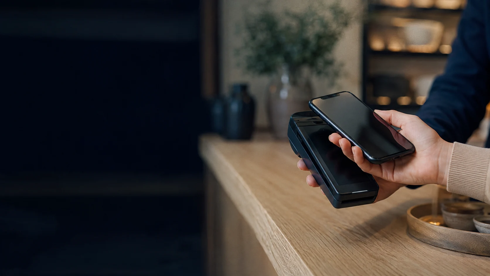 Illustrative close-up of a smartphone and payment terminal in a retail shop